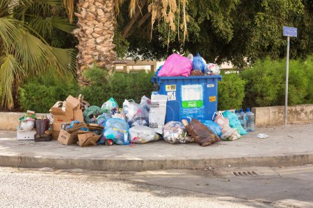 Foto de Limassol, Cyprus - October 24, 2020 - Plastic and paper garbage in the city street, waiting waste trucks. - Imagen libre de derechos