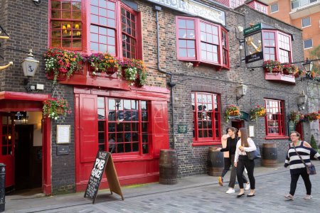Photo for London, United Kingdom - September 21, 2021 - Unidentified people walking at famous Tha Anchor pub with red doors and windows. - Royalty Free Image