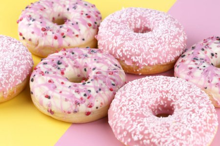 Foto de Muchas rosquillas frescas de colores sobre fondo rosa y amarillo. - Imagen libre de derechos