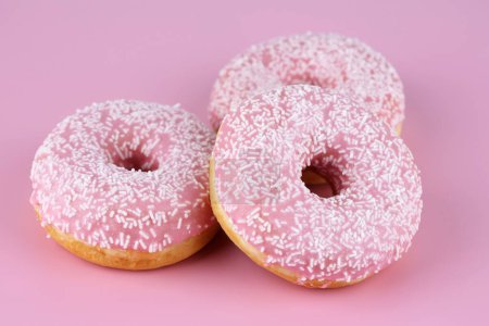 Foto de Tres rosquillas frescas sobre fondo rosa. - Imagen libre de derechos