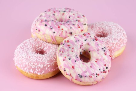 Foto de Muchos donuts frescos de colores sobre fondo rosa. - Imagen libre de derechos