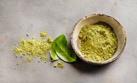 Photo for Green matcha powder with tea leaves on gray background - Royalty Free Image
