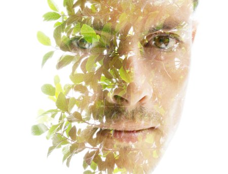Téléchargez les photos : Portrait d'un visage d'homme disparaissant dans les feuilles vertes et les branches en double exposition - en image libre de droit