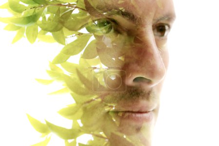 Téléchargez les photos : Un portrait rapproché d'un homme à la recherche combinée avec une photo de feuilles vertes en double exposition technique - en image libre de droit