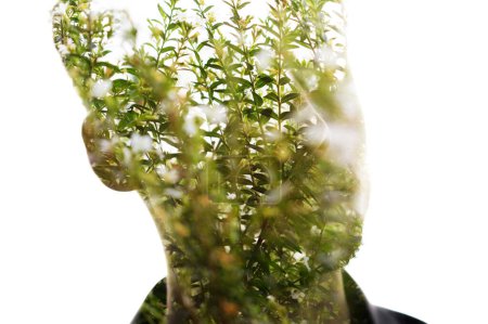 Téléchargez les photos : Portrait d'un homme aux traits faciaux flous associé à une photo de feuilles et de tiges vertes en double exposition - en image libre de droit