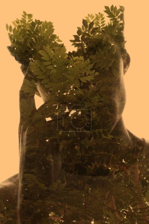 Téléchargez les photos : Une silhouette portrait d'un homme tenant une main sur son visage. Combiné avec une silhouette de branches d'arbres avec des feuilles d'une manière artistique sur fond jaune. - en image libre de droit