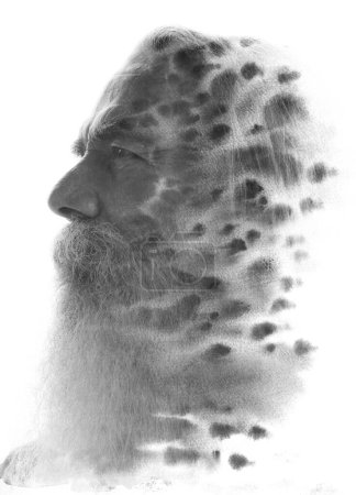 Ein schwarz-weißes Profil eines alten bärtigen Mannes mit Schnurrbart verschmilzt mit einem Tuschfleckenmuster in einer Paintgoraphie