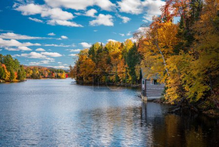 Photo for Autumn leaves and trees surround boathouse on Chateaugay Lake in Ellenburg New York State - Royalty Free Image
