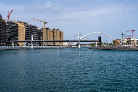 Photo for Cranes around new construction of apartments alongside the Dubai Canal with Tolerance bridge behind - Royalty Free Image
