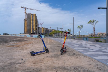 Photo for Dubai, UAE - April 2, 2023: Abandoned scooters by new construction of apartments alongside the Dubai Canal - Royalty Free Image