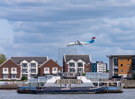 Photo for Woolwich, London - 15 May 2023: Luxair plane flying low over apartment block for landing at City Airport - Royalty Free Image