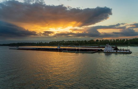 Téléchargez les photos : Coucher de soleil spectaculaire sur une péniche transportant du charbon le long du fleuve Mississippi à Baton Rouge Louisiane en direction de Port Allen - en image libre de droit