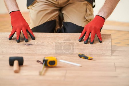 Téléchargez les photos : Revêtement de sol en vinyle. Travailleur installant des planches avec sous-pose à la maison plancher rénovation. - en image libre de droit