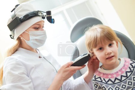 Foto de Pediatra examinando pequeña paciente femenina con otoscopio, examen de oído de un niño pequeño en la clínica - Imagen libre de derechos