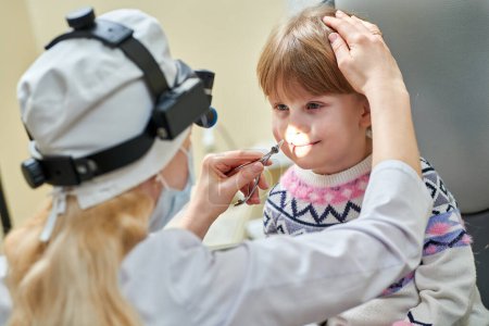Foto de Pediatra examinando a una pequeña paciente femenina. examen de nariz de un niño pequeño en la clínica - Imagen libre de derechos