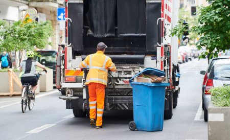 Foto de Trabajador de reciclaje municipal urbano camión recolector de basura carga de residuos y papelera - Imagen libre de derechos