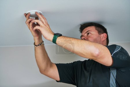 Téléchargez les photos : Travailleur électricien installant la lampe sur plafond tendu à l'intérieur - en image libre de droit