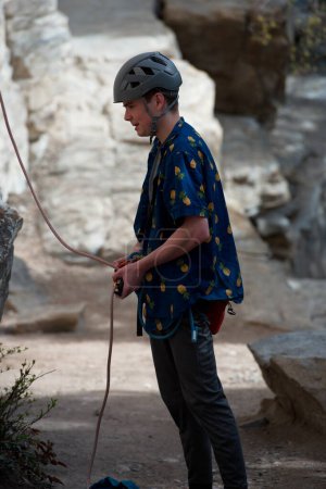 Téléchargez les photos : Homme grimpeur attachant la corde à harnais avant d'assurer un autre grimpeur. - en image libre de droit