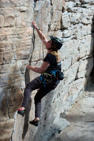 Téléchargez les photos : Homme grimpeur sur la paroi rocheuse montrant la position du pied et atteignant la poignée de la main - en image libre de droit