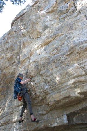 Téléchargez les photos : Homme grimpeur sur la face rocheuse positionnant les pieds sur la face rocheuse - en image libre de droit