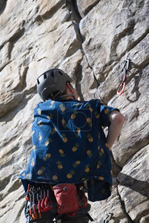 Téléchargez les photos : Arrière du grimpeur mâle après avoir fixé le tirage rapide atteignant la corde à attacher au tirage rapide. - en image libre de droit