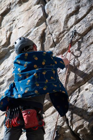 Photo for Back of male climber attaching climbing rope to quick draw - Royalty Free Image