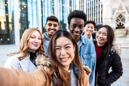 Foto de Multiracial people taking a selfie together and making funny faces - Happy friendship and diversity concepts with mixed race young best friends having fun in the city - Imagen libre de derechos