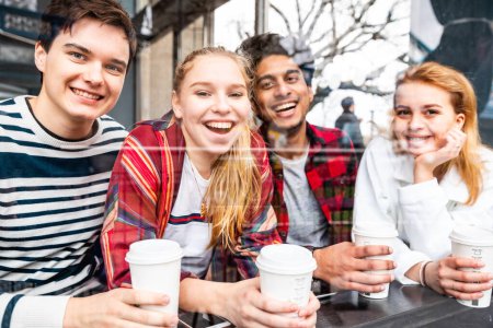 Foto de Felices amigos multirraciales en un café en Londres - Grupo multirracial de adolescentes mejores amigos disfrutando de un café juntos - Estilo de vida y comida y bebida en Londres - Imagen libre de derechos