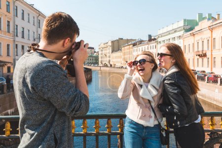 Foto de Grupo de amigos disfrutando del día en San Petersburgo y tomando fotos - Tres jóvenes felices, un hombre y dos mujeres, divirtiéndose juntos - Conceptos de amistad y estilo de vida - Imagen libre de derechos