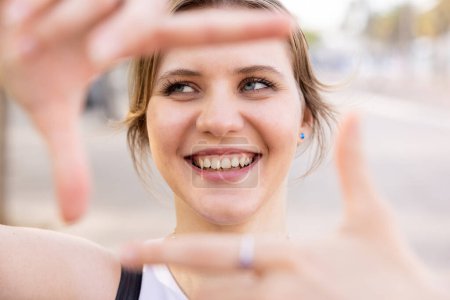 Foto de Sonriente mujer joven feliz gesto marco con las manos, sonriendo y mirando hacia otro lado - Retrato de la hermosa mujer caucásica disfrutando de un día en Barcelona - Imagen libre de derechos