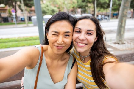 Foto de Dos mujeres mejores amigas abrazando y tomando una selfie - mujeres caucásicas y asiáticas juntas en Barcelona, amistad, ciudad multicultural y conceptos de amor con personas reales - Imagen libre de derechos