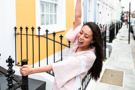 Foto de Mujer china feliz y riendo disfrutando de un día en Notting Hill Londres - Mujer joven asiática explorando el colorido barrio de Londres y divirtiéndose - Estilo de vida y turismo - Imagen libre de derechos