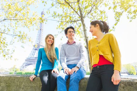 Téléchargez les photos : Trois amis joyeux qui s'amusent ensemble dans un parc ensoleillé de Paris au bord de la Seine et de la Tour Eiffel - Des amis qui rient et passent du temps dehors à Paris - en image libre de droit