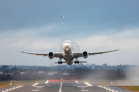 Foto de Aviones despegando y aterrizando durante una tormenta en Inglaterra - Aviones que salen en primer plano y otro que se acerca en segundo plano - Conceptos de viaje y transporte - Imagen libre de derechos