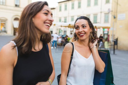 Foto de Dos mujeres paseando por las calles de la ciudad con coloridas bolsas de compras - Compras mejores amigos disfrutando de la terapia al por menor en Italia - Imagen libre de derechos