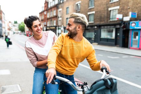 Téléchargez les photos : Heureux couple caucasien en vélo à Londres - jeune homme et jeune femme souriant et riant utilisant un service de vélo partagé dans la ville - mode de vie, Voyage et bonheur - en image libre de droit