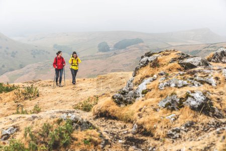Téléchargez les photos : Deux jeunes femmes passent la journée en plein air en randonnée dans la nature à travers le Peak District au Royaume-Uni - Nature et concepts de voyage - en image libre de droit