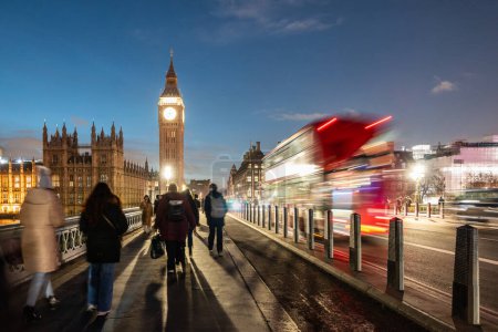 Téléchargez les photos : Touristes et la circulation sur le pont Westminster à Londres au crépuscule - scène de rue de Londres la nuit avec bus rouge et Big Ben - en image libre de droit