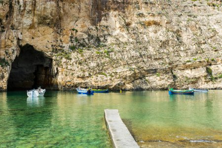 Foto de Barcos de recreo en la escarpada costa delimitada por escarpados acantilados de piedra caliza, y salpicados de profundas cuevas en Malta. El Mar Interior es una laguna de agua de mar en la isla de Gozo unida al Mar Mediterráneo a través de una abertura formada por un estrecho natur - Imagen libre de derechos