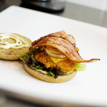 Téléchargez les photos : Burger with chicken and bacon on the kitchen table in the restaurant - en image libre de droit