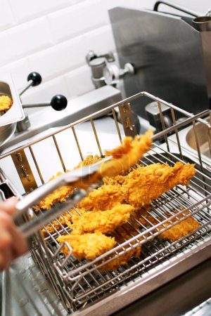 Téléchargez les photos : Cooking breaded chicken slices in the kitchen in a restaurant - en image libre de droit