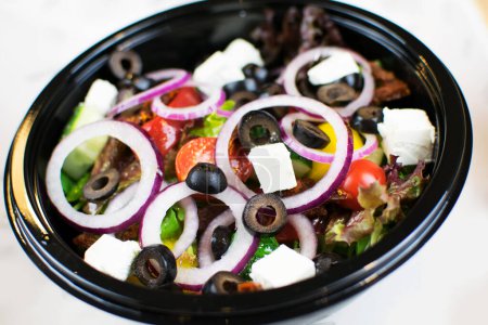 Téléchargez les photos : Salade végétarienne en plastique noir sur fond blanc - en image libre de droit