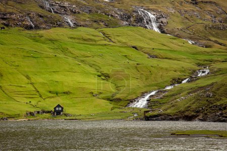 Foto de Casa solitaria y cascadas en la zona de Saksun en las islas Feroe - Imagen libre de derechos
