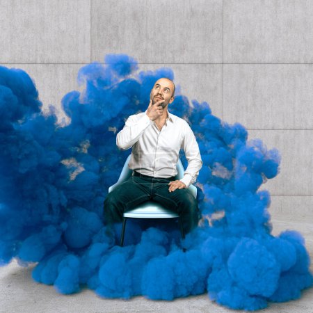Téléchargez les photos : Cher homme assis enveloppé dans la fumée bleue, concept de créativité - en image libre de droit