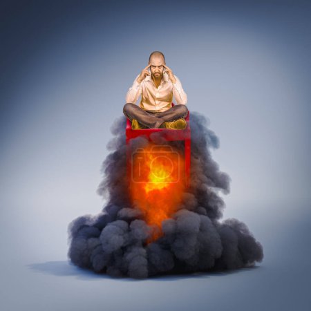 Foto de Pensive man sitting in a chair taking flight with flames and smoke. - Imagen libre de derechos