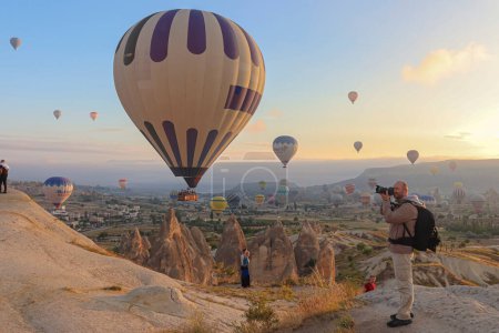 Téléchargez les photos : GOREME/TURKEY - June 29, 2022: photographer intent on photographing the hot air balloons flying above Goreme - en image libre de droit