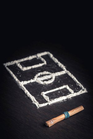 Foto de Rolled up banknote and football field drawn with cocaine drugs - Imagen libre de derechos