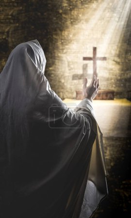 Photo for Person praying in a cassock with a crucifix in front of him - Royalty Free Image