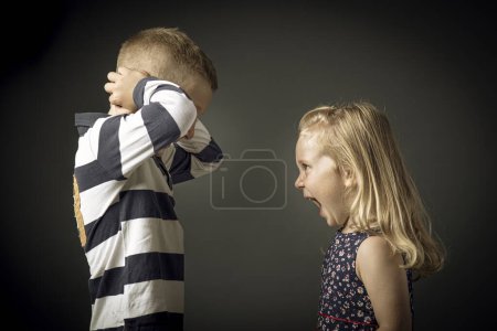 Téléchargez les photos : Enfant crie et l'enfant branle ses oreilles afin de ne pas entendre - en image libre de droit
