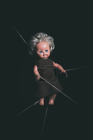 Téléchargez les photos : Vieille poupée attachée sur fond noir - en image libre de droit